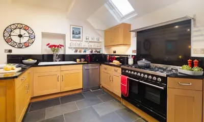 a kitchen with wooden cabinets and a black stove top oven at Crow Cottage in Keswick