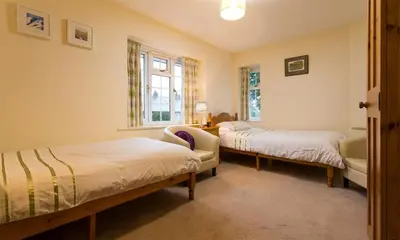 a bedroom with two beds and a chair and a window at Grange Fell Borrowdale in Keswick