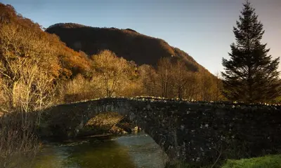 a stone bridge over a river in front of a mountain at Grange Fell Borrowdale in Keswick