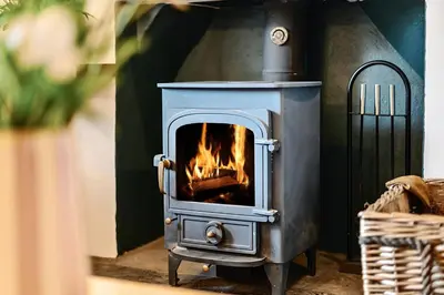a stove with a fire in a room at Oakbank in Elterwater