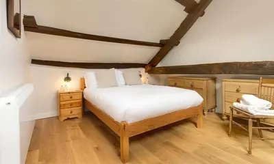 a bedroom with a bed and a chair in it at Barn Cottage in Cockermouth