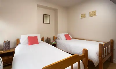 a bedroom with two beds with white and red pillows at Barn Cottage in Cockermouth