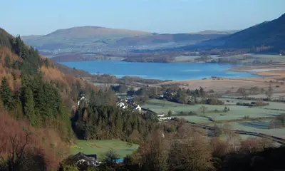 a view of a valley with a lake and mountains at Barn Cottage in Cockermouth