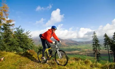 a man riding a bike on a hill at Barn Cottage in Cockermouth