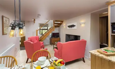 a living room with red chairs and a table at Barn Cottage in Cockermouth