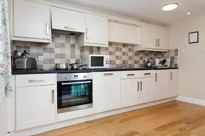 a kitchen with white cabinets and a microwave at Low Croft Cottage in Grasmere