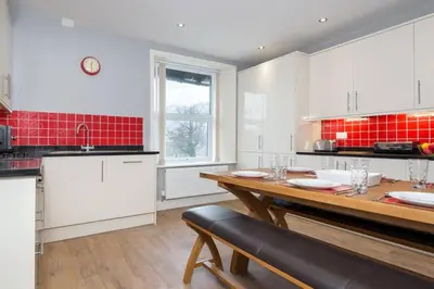 a kitchen with white cabinets and a wooden table at Lake Road Apartment Keswick in Keswick