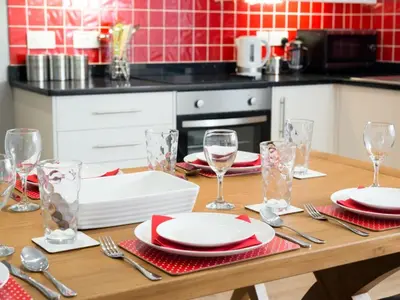 a wooden table with plates and wine glasses on it at Lake Road Apartment Keswick in Keswick