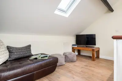 a living room with a leather couch and a television at Lake Road Apartment Keswick in Keswick