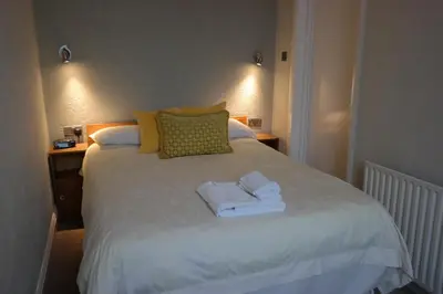a bedroom with a white bed with towels on it at Arrandale Apartments in Douglas