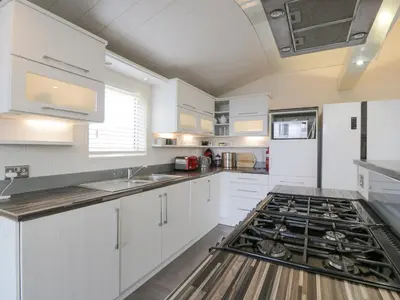 a kitchen with white cabinets and a stove top oven at Oyster Bay Lodge in Dalbeattie