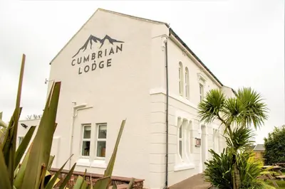 a white building with a mountain logo on it at Cumbrian Lodge in Seascale