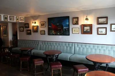 a waiting room with a blue couch and tables at The Steam Packet Inn in Isle of Whithorn