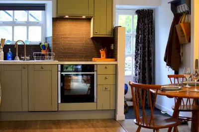 a kitchen with green cabinets and a table and a sink at Bottom Shop, Elterwater in Chapel Stile