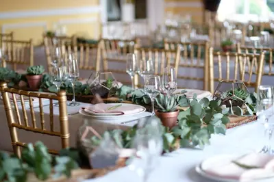 a table with plates and glasses and potted plants on it at The Gretna Chase Hotel in Gretna