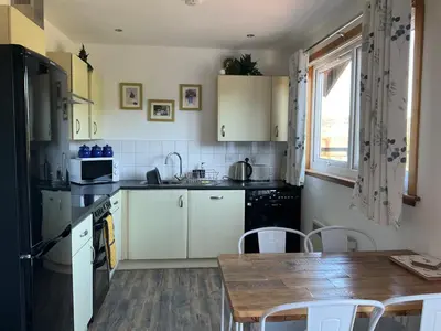 a kitchen with white cabinets and a wooden table at Heron Lodge, edge of Mabie Forest Dumfries in Dumfries
