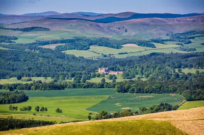 a view of a green valley with a castle in the distance at Stableyard Studio: Drumlanrig Castle in Thornhill