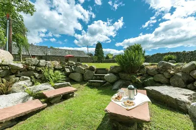 a table and benches in a garden with rocks at Bridge End Farm Cottages in Boot