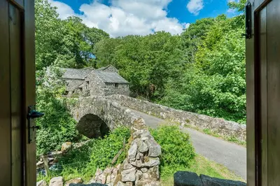 an old stone building on a bridge over a road at Bridge End Farm Cottages in Boot