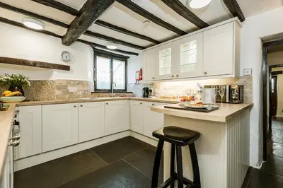 a kitchen with white cabinets and a bar stool at Bridge End Farm Cottages in Boot