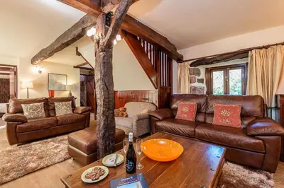 a living room with leather furniture and a tree at Bridge End Farm Cottages in Boot