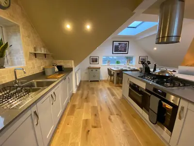 a kitchen with white cabinets and a wooden floor at Latrigg View in Keswick