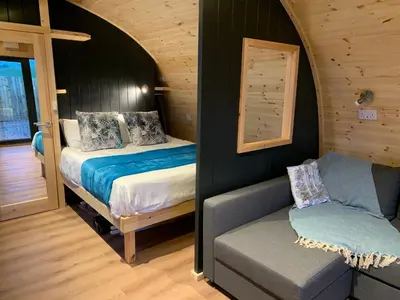 a bedroom with a bed and a couch in a room at Thistle Pod Farm Stay with Hottub Sleeps 2 in Galston