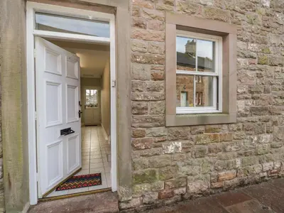 a white door on a brick wall with a window at The Crook in Penrith