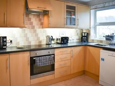 a kitchen with wooden cabinets and a stove top oven at Eskin Den in Keswick