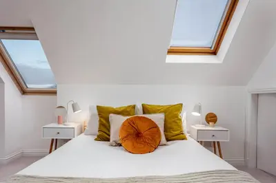 a bedroom with a large white bed with yellow pillows at Sunset View - Donnini Apartments in Ayr