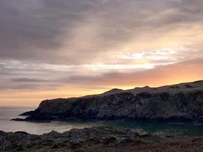 a sunset over a rocky island in the ocean at Fern Forest House- Uk31047 in Portpatrick