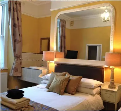 a bedroom with a bed with a large mirror at Melrose Guest House in Douglas