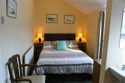 a bedroom with a bed with two tables and two lamps at Melrose Guest House in Douglas