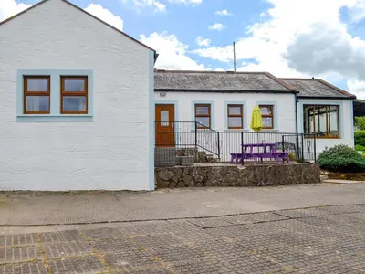 a white house with a purple bench in front of it at Laird House in Lochmaben