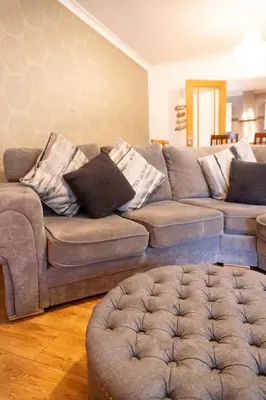 a living room with a couch and an ottoman at Four Oaks Cottage in Rockcliffe