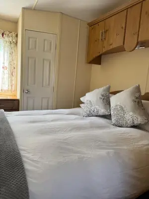 a white bed with two pillows on top of it at Happydays Caravan 1 Newton Stewart in Bailliewhir