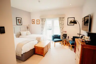 a hotel room with two beds and a desk at The Fleece at Ruleholme in Carlisle