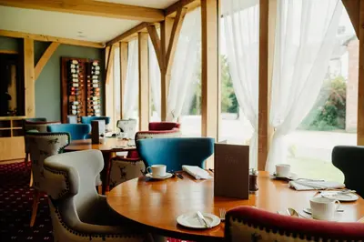 a restaurant with tables and chairs and a large window at The Fleece at Ruleholme in Carlisle