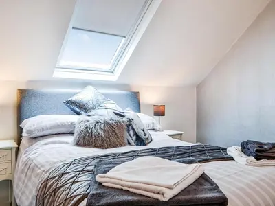 a bedroom with a large bed with a skylight at Chapel Mouse Cottage in Cockermouth