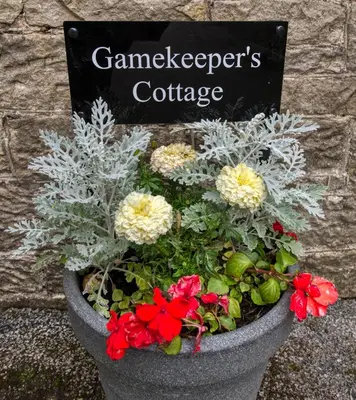 a pot of flowers in front of a sign at Tallentire Hall in Cockermouth