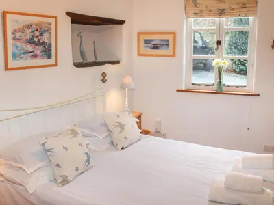 a bedroom with a white bed with pillows and a window at Plosh House in Keswick
