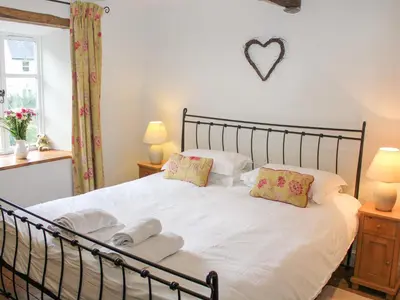 a bedroom with a white bed with two pillows at Plosh House in Keswick