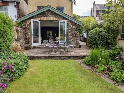 a patio with a table and chairs in a yard at Plosh House in Keswick