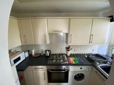 a kitchen with white cabinets and a stove top oven at Robinsons Cottage, central and quiet in Cockermouth