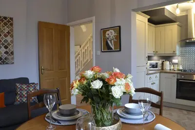 a dining room table with a vase of flowers on it at Stunning Period Townhouse with Garden, Walking Distance to Town in Dumfries