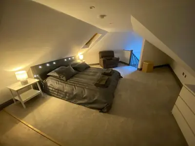 a bedroom with a bed and a chair in a attic at holidayhomemoffat,com (Stable Cottage) in Moffat