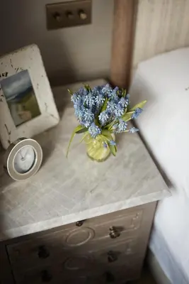 a vase of flowers on a table next to a bed at Little Nut Cottage in Ambleside