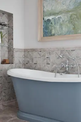 a white bath tub in a bathroom with a painting at Little Nut Cottage in Ambleside