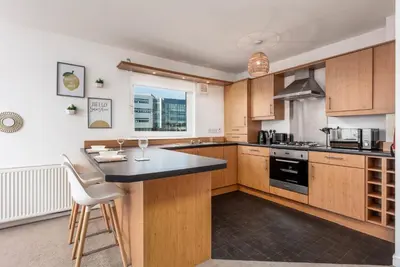 a kitchen with wooden cabinets and a black counter top at Walker Suite No52 - Donnini Apartments in Kilmarnock