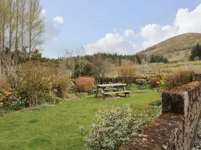a picnic table in a garden with a hill in the background at Glen Cottage in Penrith
